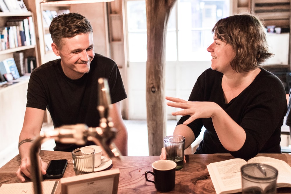 man and woman sitting on chairs front of table